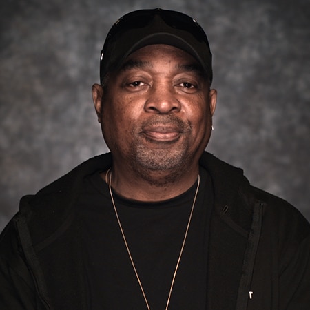 Chuck D looking into camera in front of a dark background